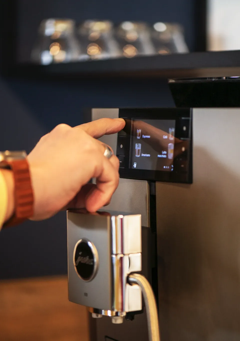Main sélectionnant un expresso sur l'écran tactile d'une machine à café Jura professionnelle en entreprise